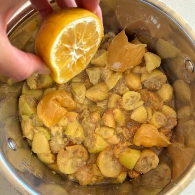 Feijoa Leather A hand squeezes a lemon half over a pot containing chopped figs and dollops of what appears to be honey or syrup.