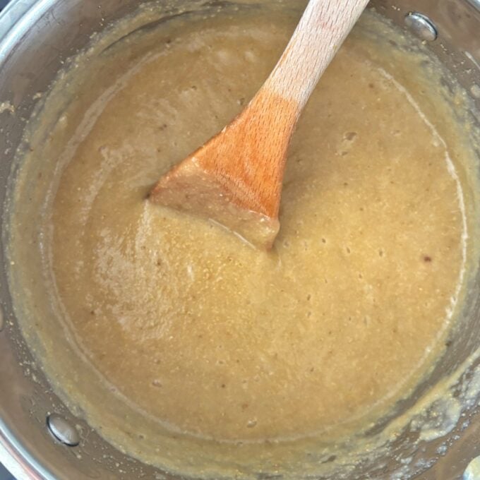 Feijoa Leather A pot of thick, light brown batter being stirred with a wooden spoon.