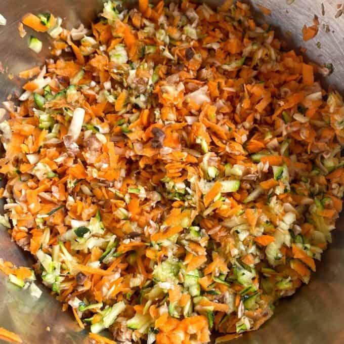 Veggie-Packed Meatballs A close-up of a metal bowl filled with finely chopped or grated carrots, zucchini, and mushrooms mixed together.