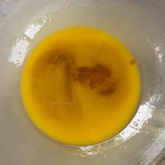 Apricot Bumper Bars A bowl containing melted butter mixed with brown sugar, creating a smooth, amber-colored liquid.