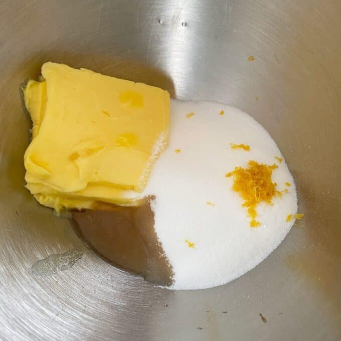 Bakewell Tart Butter, granulated sugar, orange zest, and a liquid ingredient are placed together in a metal mixing bowl.