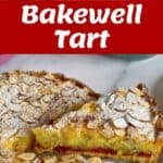 A Bakewell tart topped with sliced almonds and powdered sugar, sliced to show a layer of jam and frangipane filling.