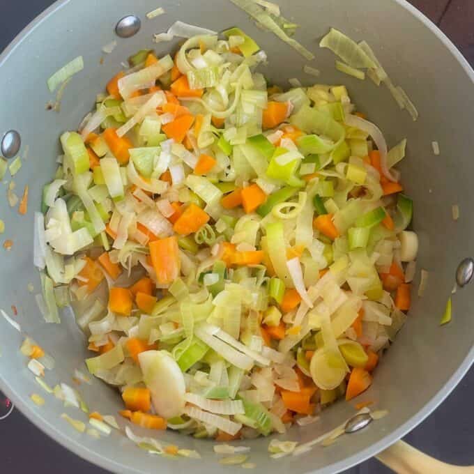 Chicken and Leek Pie Chopped carrots, leeks, and celery are being sautéed in a large pot.