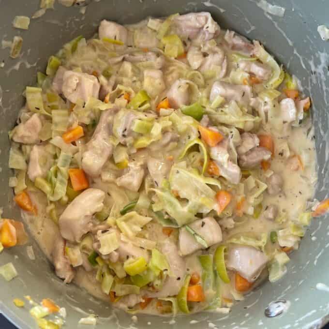Chicken and Leek Pie A pot filled with chopped chicken, carrots, leeks, and onions in a creamy white sauce.