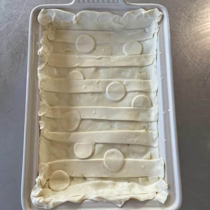 Chicken and Leek Pie A rectangular baking dish lined with pastry strips and circular pastry cutouts, ready for baking.