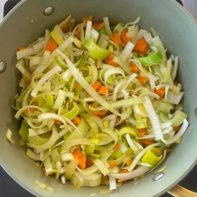 Chicken and Leek Pie Sliced leeks, carrots, and onions cooking in a large pot.