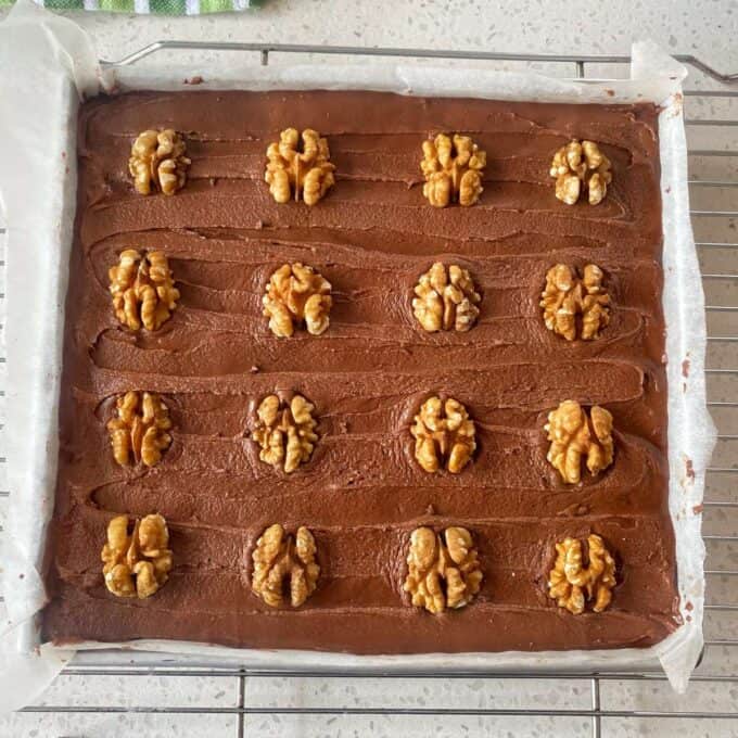 Chocolate Cornflake Slice A rectangular tray of chocolate brownies topped with rows of whole walnut halves, placed on a wire cooling rack.