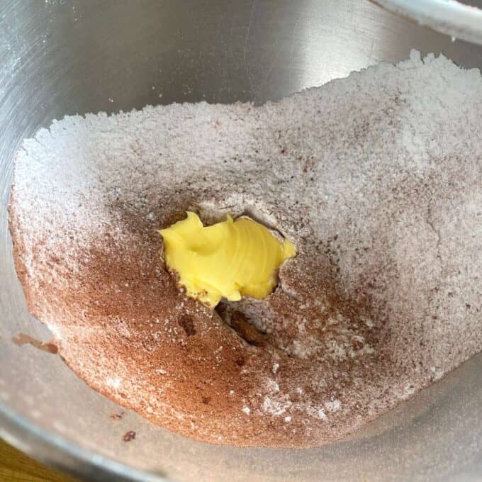 Chocolate Cornflake Slice Mixing bowl containing flour, cocoa powder, and a dollop of butter ready to be blended for baking preparation.