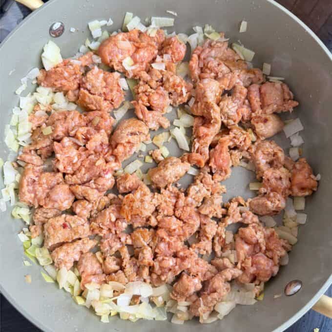 Italian Sausage Pasta Bake Ground meat and chopped onions cooking in a large pan.