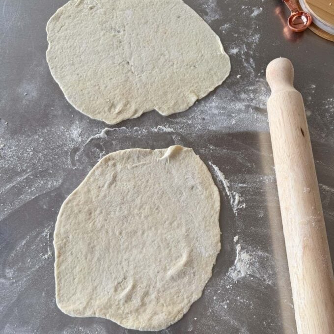 Lamb Koftas on Homemade Flatbreads Two rolled-out pieces of dough on a floured surface next to a wooden rolling pin.