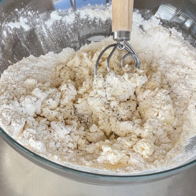 Lamb Koftas on Homemade Flatbreads A glass bowl containing flour and butter mixture being blended with a pastry cutter, likely in preparation for baking.