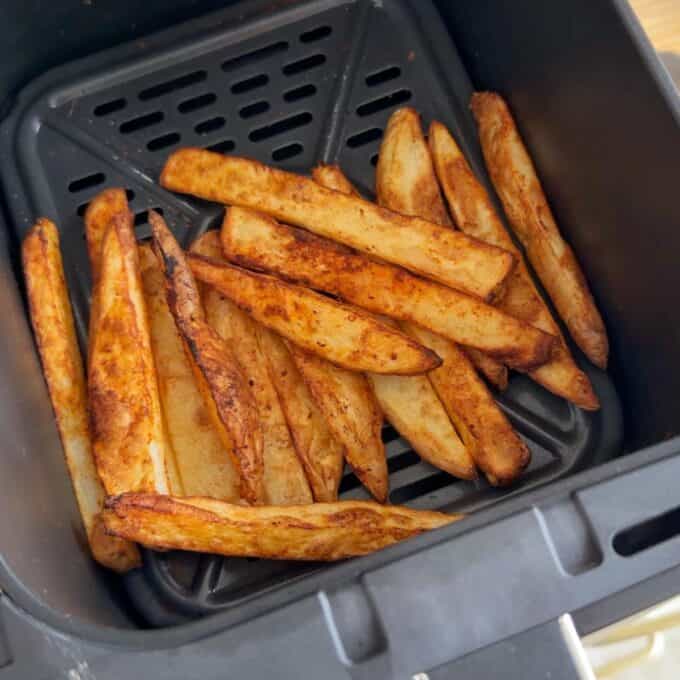 Lamb Koftas on Homemade Flatbreads Thick-cut potato wedges are arranged in a single layer inside an air fryer basket, cooked to a golden brown.