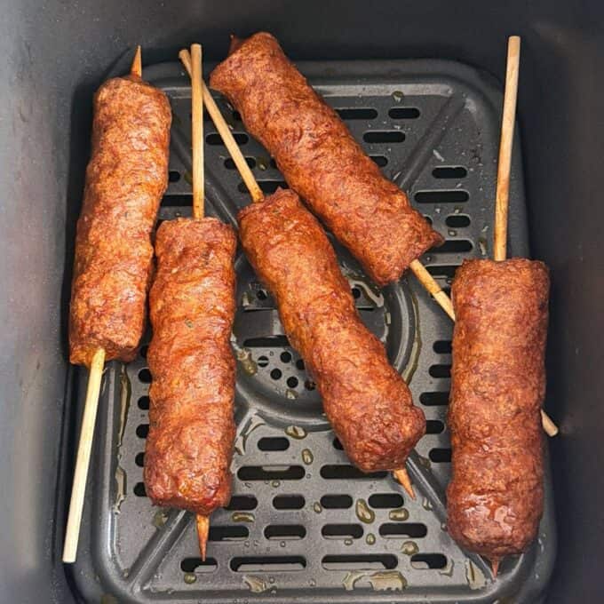 Lamb Koftas on Homemade Flatbreads Five cooked meat skewers are placed inside an air fryer basket.
