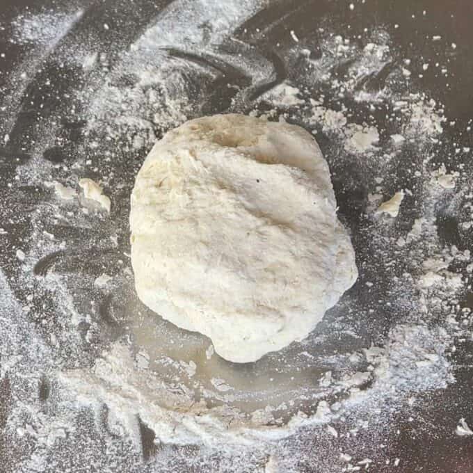 Lamb Koftas on Homemade Flatbreads A ball of raw dough sits on a floured surface, surrounded by scattered flour.
