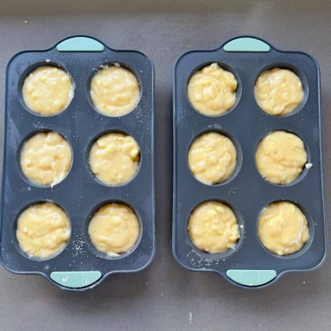 Lemon, Yoghurt and White Chocolate Muffins Two silicone muffin trays filled with unbaked muffin batter are placed on a countertop, ready to be baked.