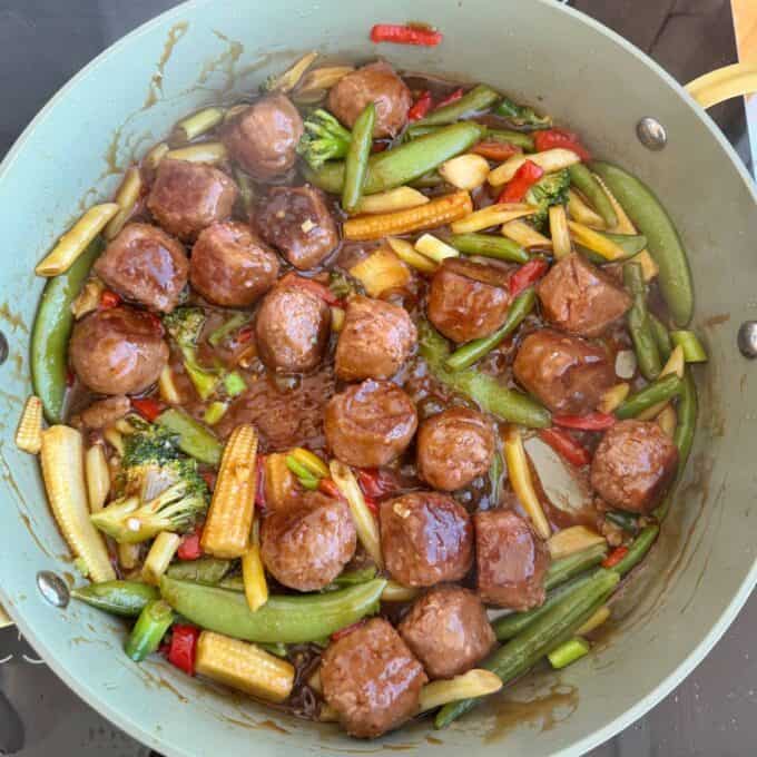 Meatball Noodle Stir Fry Pan filled with meatballs, baby corn, snap peas, red bell peppers, and broccoli in a brown sauce.