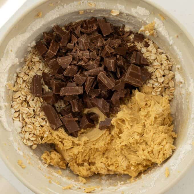 Oaty Choc Chunk Cookie Bars A mixing bowl containing oats, chocolate chunks, and cookie dough ready to be combined.