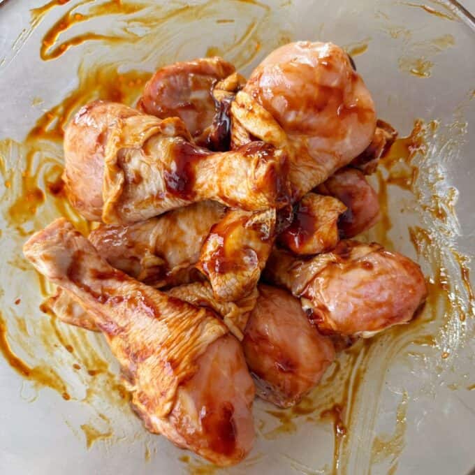 Teriyaki Chicken Drumsticks Raw chicken drumsticks coated with marinade in a glass bowl.