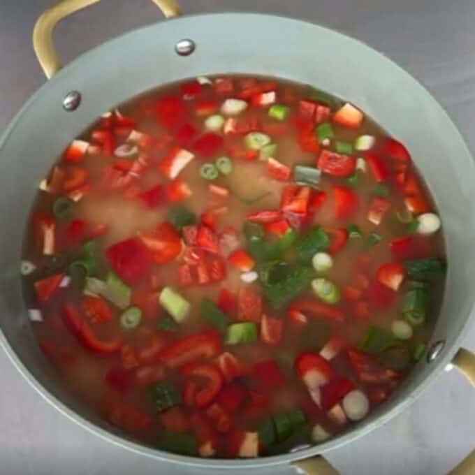 Teriyaki Chicken Drumsticks A pot of soup with chopped red bell peppers, green onions, and other vegetables simmering in broth.