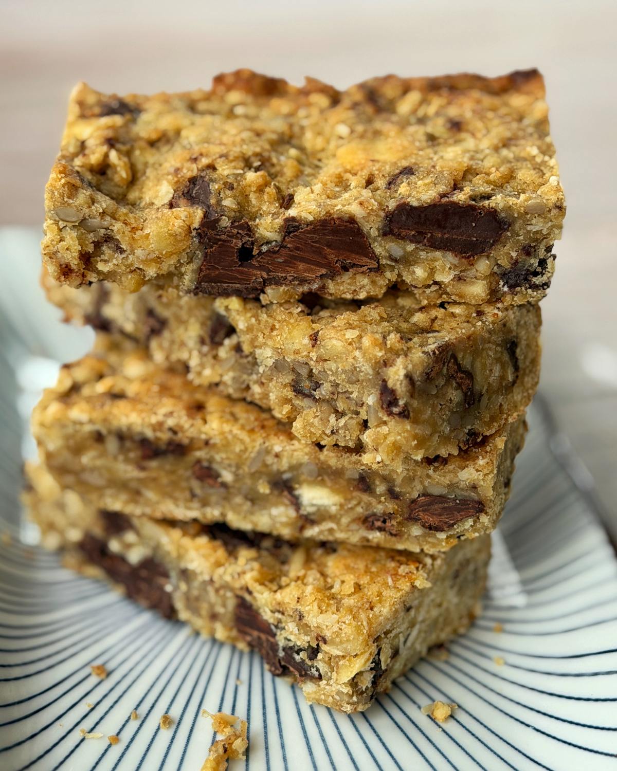 Four stacked oatmeal cookie bars with visible chocolate chunks on a patterned plate.