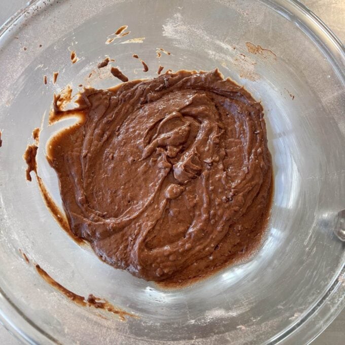 Microwave Self-Saucing Chocolate Pudding A glass bowl containing chocolate cake batter on a lightly floured surface.