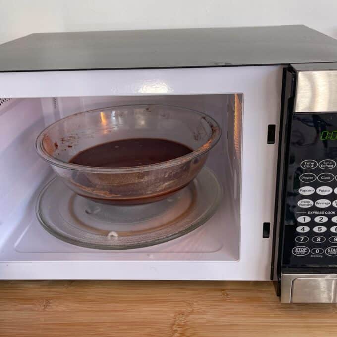 Microwave Self-Saucing Chocolate Pudding A glass bowl with chocolate mixture sits on the turntable inside an open microwave oven.