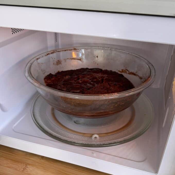 Microwave Self-Saucing Chocolate Pudding A glass dish containing a baked chocolate dessert sits on the turntable inside a microwave oven.