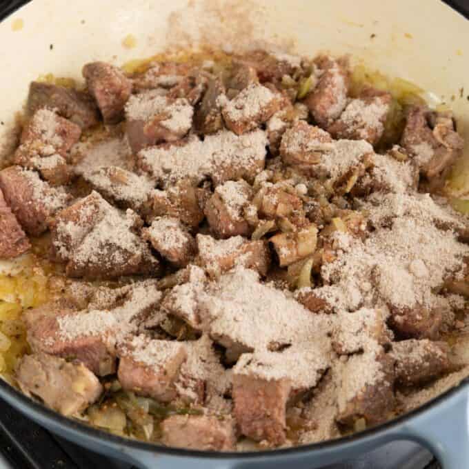 Shepherd's Pie Chunks of beef and chopped onions are cooking in a pot, topped with a layer of flour.