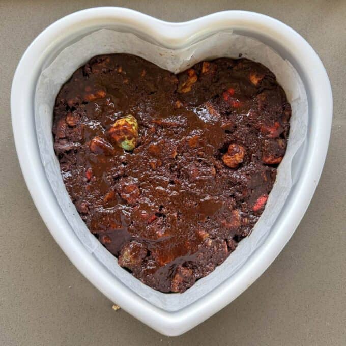 Love Heart Lolly Slice A heart-shaped baking tin filled with unbaked chocolate brownie mixture containing visible chunks and pieces on the surface.