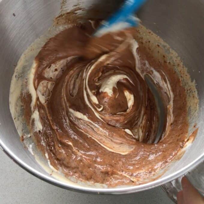 Simple Chocolate Mousse A metal mixing bowl containing chocolate and vanilla batter being swirled together with a spatula.