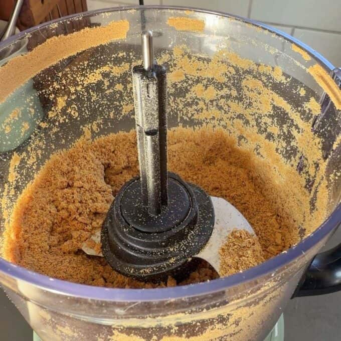 No-Bake Gingernut Slice Crushed graham crackers inside a food processor, with crumbs coating the sides and blade.