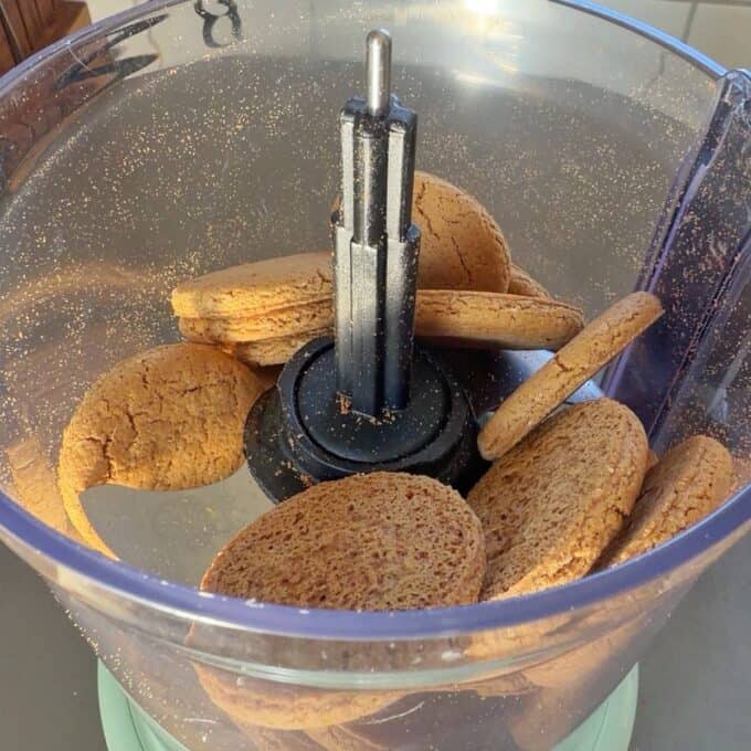 No-Bake Gingernut Slice Several brown cookies are placed inside a food processor bowl, ready to be crushed.
