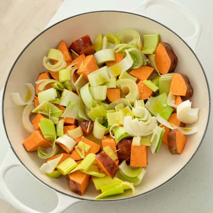 One Pot Chicken, Leek and Orzo Bake Chopped sweet potatoes and leeks in a white pot, ready to be cooked.