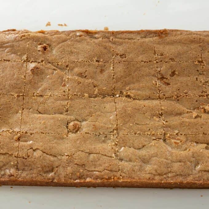 Hot Cross Blondies A large rectangular tray of blondies cut into squares on a white surface.