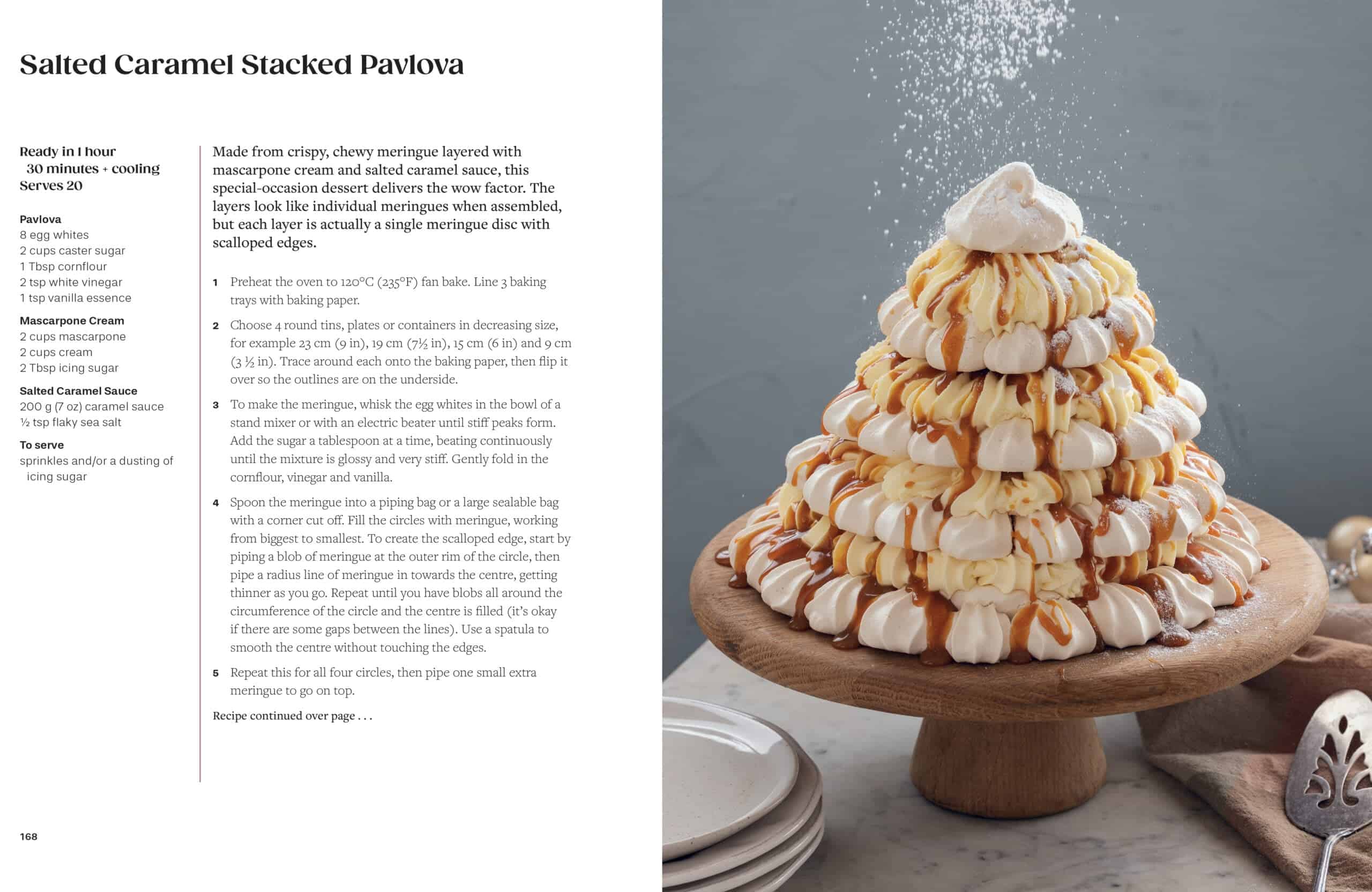 A tiered pavlova topped with whipped cream is dusted with powdered sugar on a wooden cake stand, beside a recipe for Salted Caramel Stacked Pavlova on a white background.
