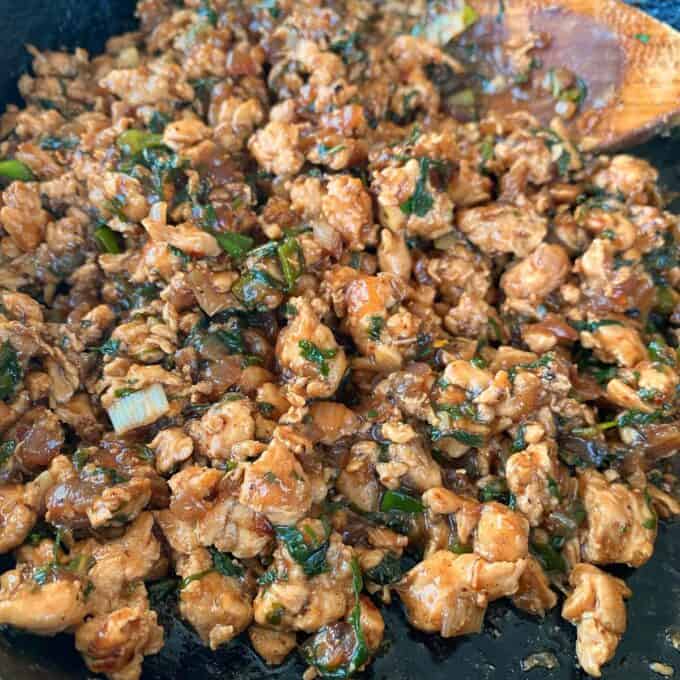 Chicken Larb Cooked ground chicken with chopped vegetables and herbs in a skillet, mixed with a brown sauce.