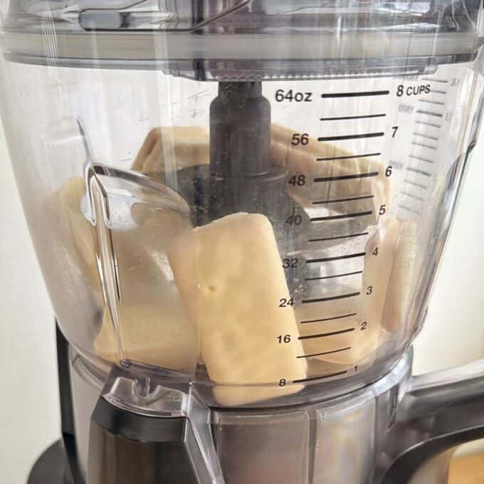 White Chocolate and Raspberry Tim Tam Balls Close-up of a food processor bowl containing several large pieces of peeled potatoes, with measurement markings visible on the side.