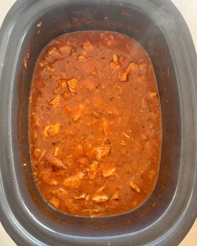 Slow Cooker Chicken Ragu A slow cooker filled with shredded chicken in a thick, red tomato-based sauce.