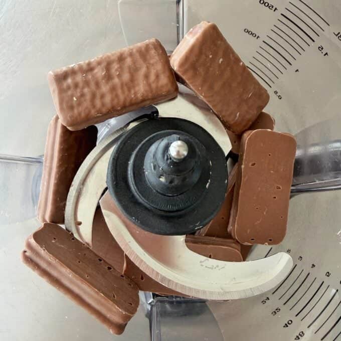 Tim Tam Cheesecake Balls Chocolate-covered rectangular biscuits arranged around the blades inside a food processor bowl, ready to be blended.