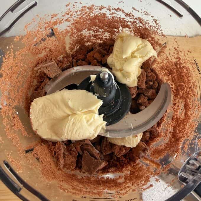 Tim Tam Cheesecake Balls Chocolate pieces and cream cheese in a food processor bowl, ready to be mixed.