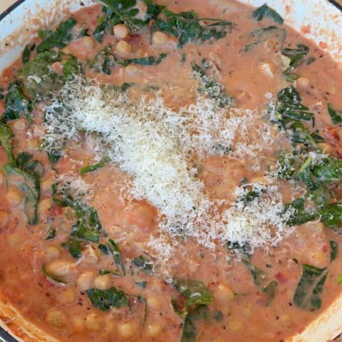 Marry Me Chickpeas and Beans A pot of creamy tomato chickpea stew with greens, topped with grated cheese.