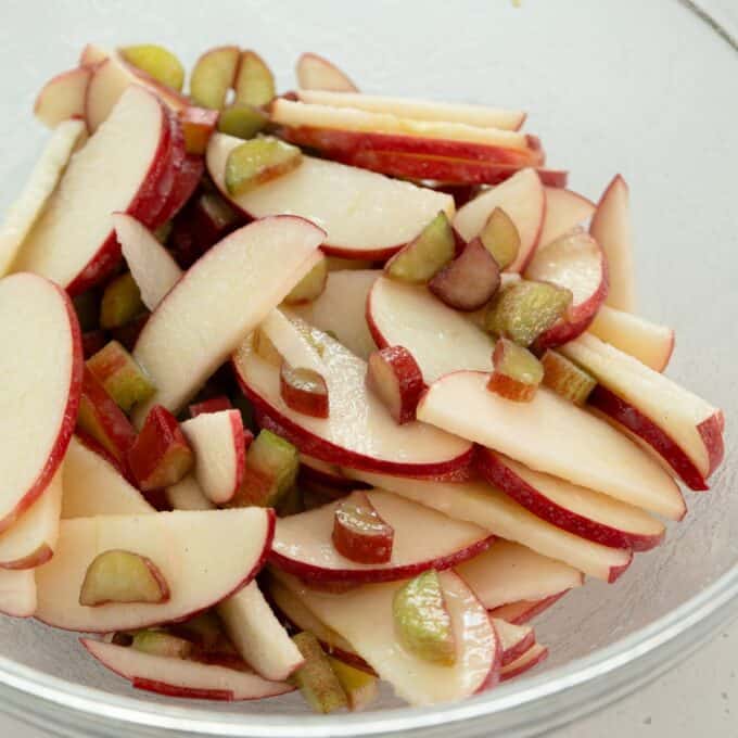Rhubarb and Apple Galette Sliced red apples and chopped rhubarb pieces in a clear glass bowl.