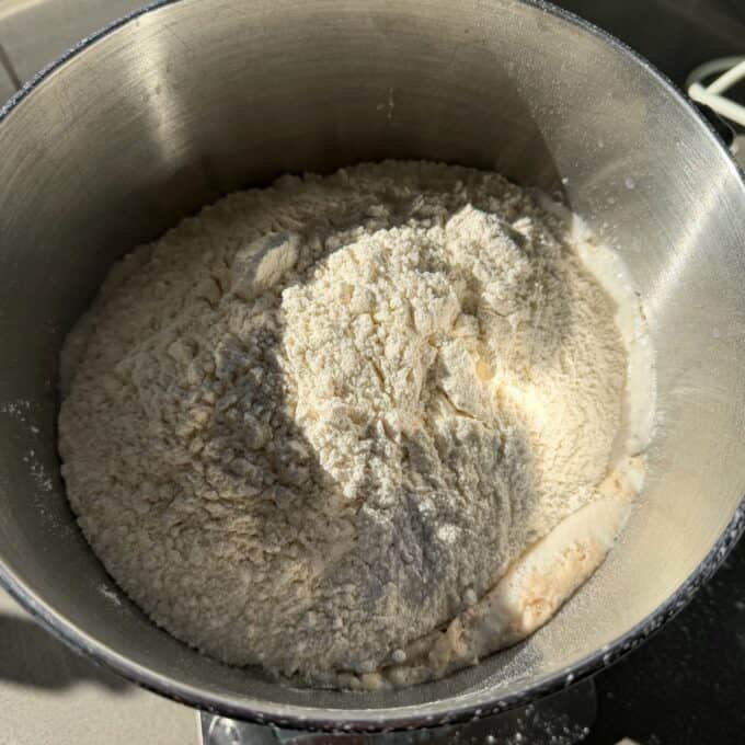 White Sandwich Bread Metal mixing bowl containing flour and other dry baking ingredients, with a small amount of liquid visible along the edge.