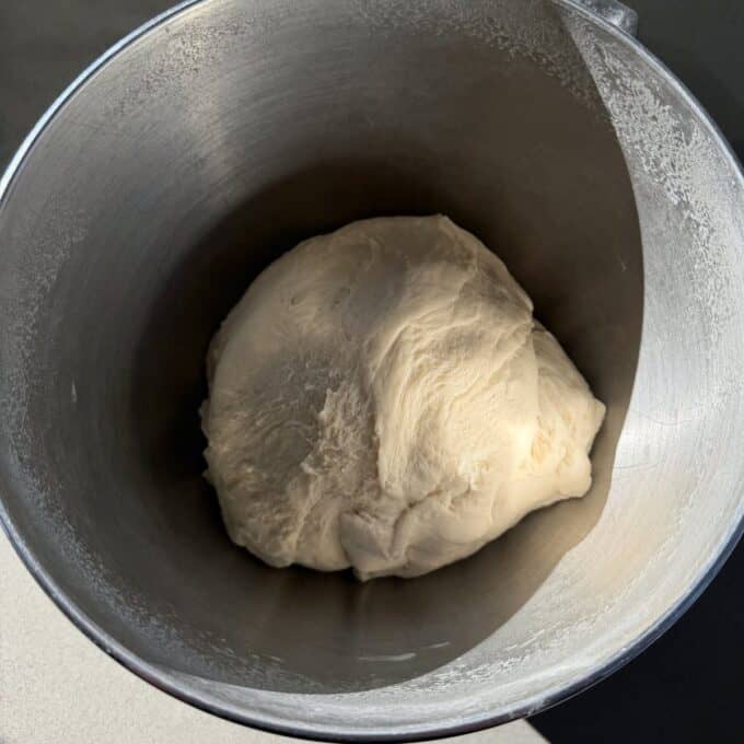 White Sandwich Bread Ball of risen bread dough resting in a metal mixing bowl, with sunlight casting a shadow inside the bowl.
