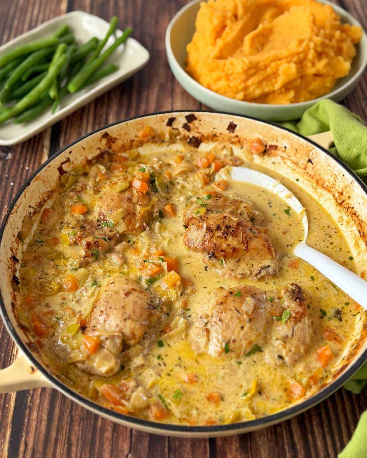 Creamy French Mustard Chicken Skillet with creamy chicken and vegetables, served with mashed sweet potatoes in a bowl and green beans on a plate.