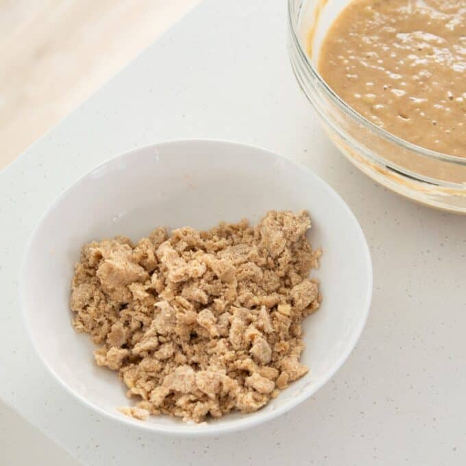 Banana Cinnamon Crumble Muffins A white bowl of crumb topping next to a glass mixing bowl filled with batter.