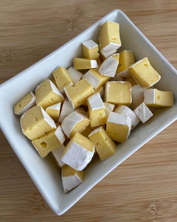 Air Fryer Cranberry Brie Dip A rectangular white dish filled with bite-sized cubes of brie cheese.