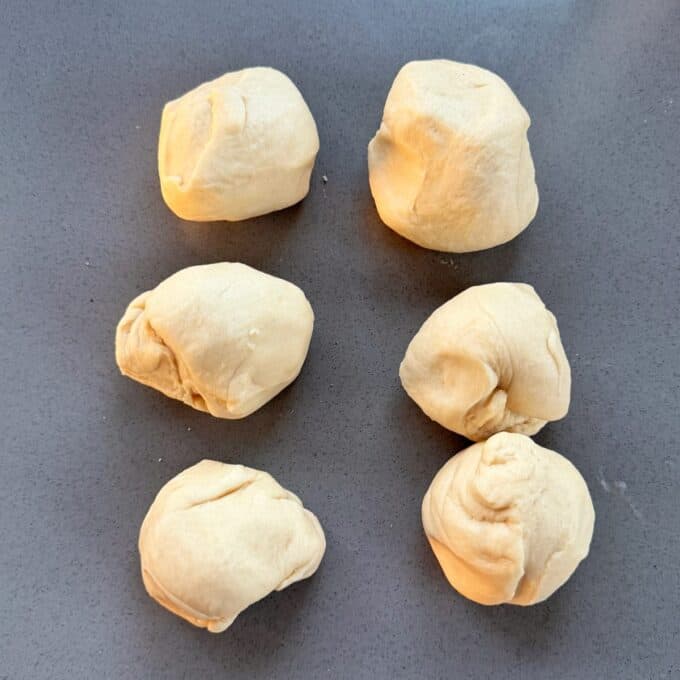 Homemade Garlic Naan Six round portions of raw dough arranged in two columns on a grey surface.