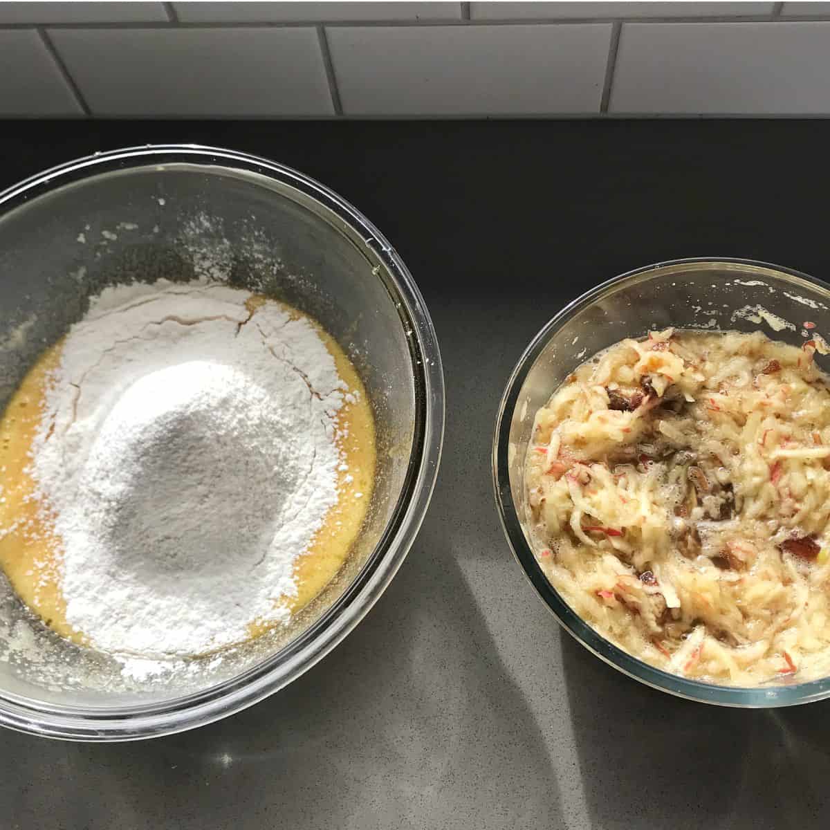 Lumberjack Cake Two glass bowls on a counter: one containing flour atop a yellow liquid mixture, and the other containing a shredded apple mixture.