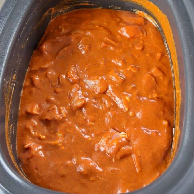 Slow Cooker Butter Chicken A slow cooker filled with a thick, reddish-orange curry or stew.